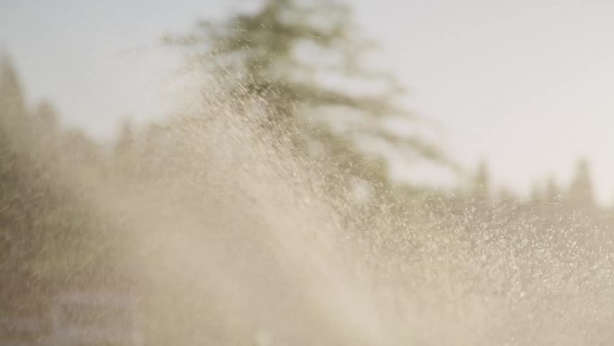Sprinkler system irrigating a field outdoors at evening