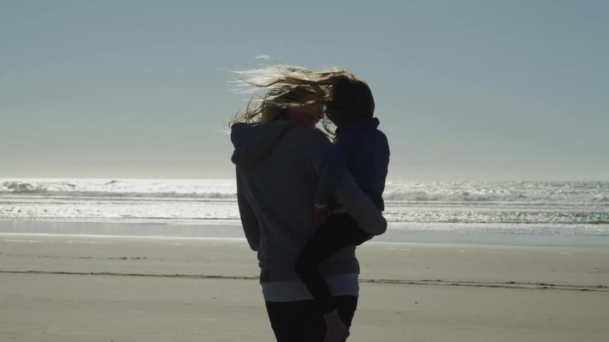 A woman and child walking on a beach