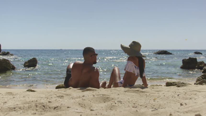 A man and woman are sitting at the beach together