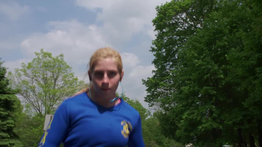 Focused woman jogging quickly down a street on a sunny day