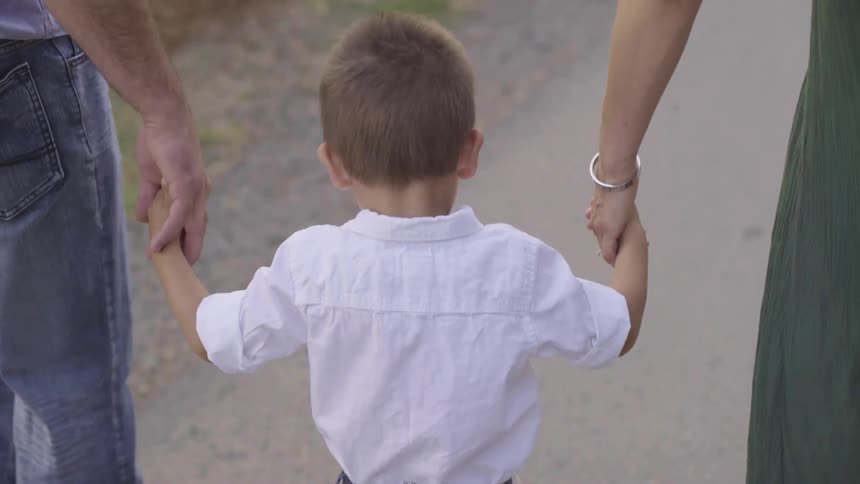 A family holding hands and walking down a path