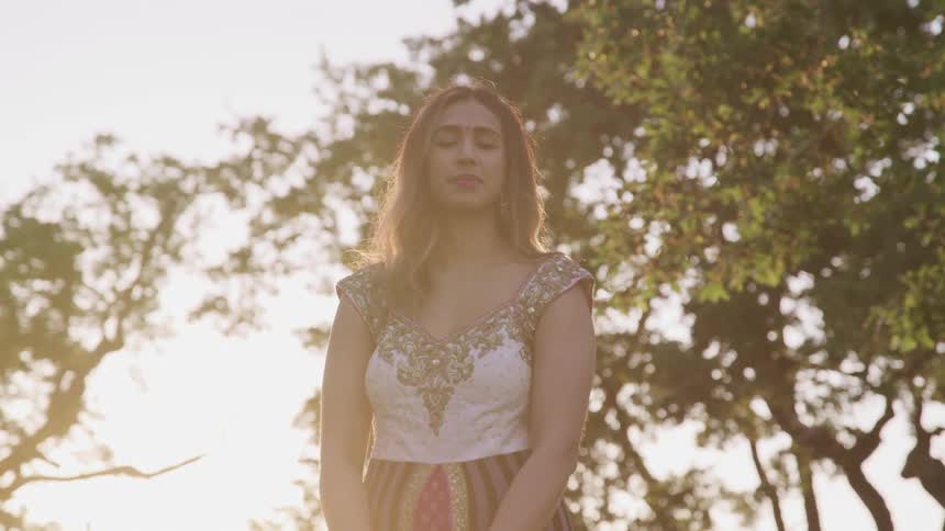 A young woman looks into the camera while standing outdoors during the day