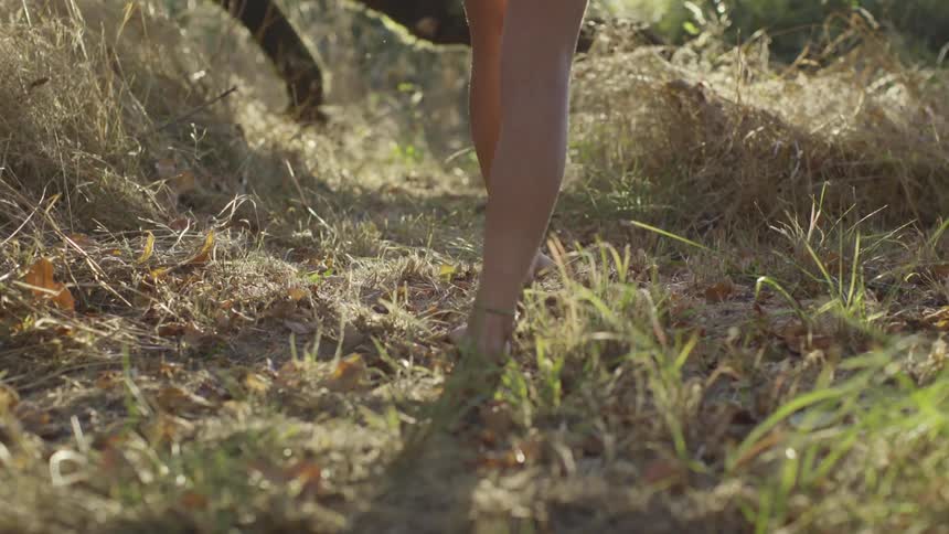 A woman is walking barefoot outdoors in spring