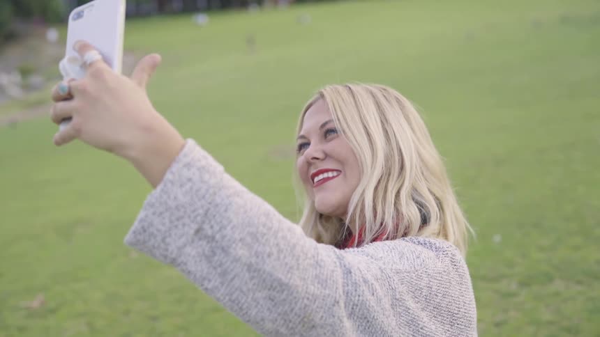 A woman talking a selfie in a park