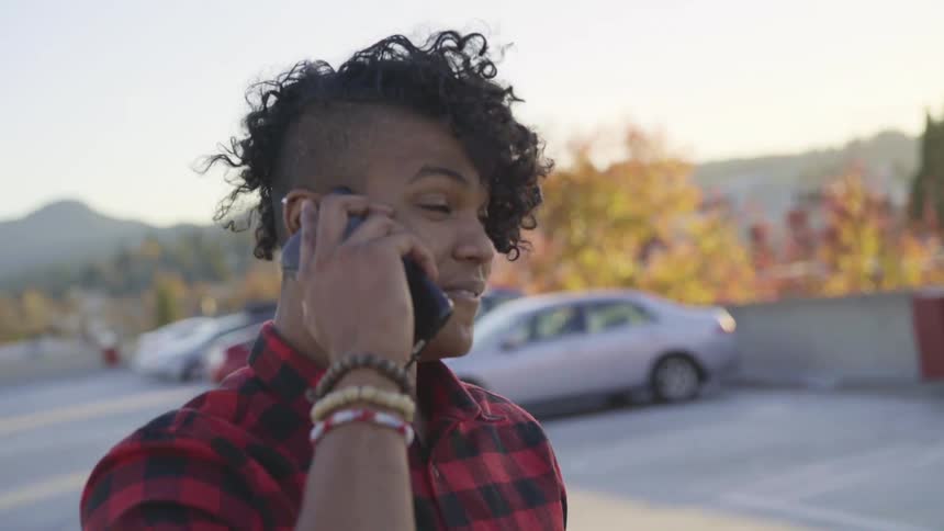 Man standing outside in a parking lot on a rooftop talking on a phone at daytime