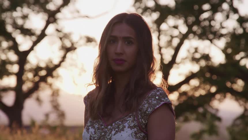 A woman is standing outdoors at dusk