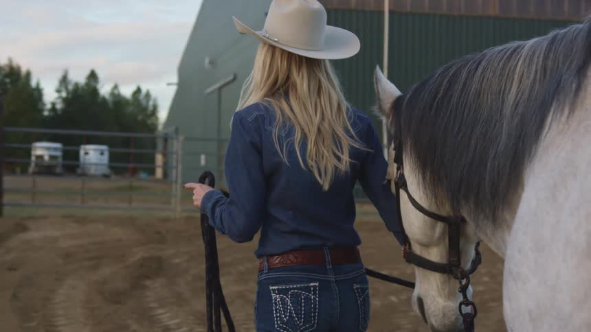 Woman walks toward corral leading horse