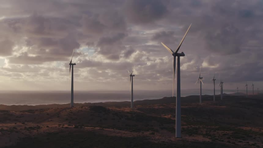 Turbines spinning on a wind farm overlooking the coast under storm clouds