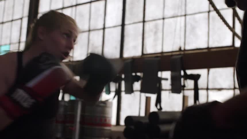 A man and woman spar in a gym
