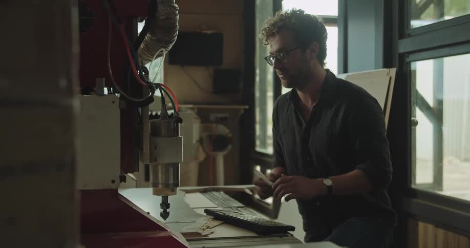 Man programming an autmatic drilling machine on a workshop