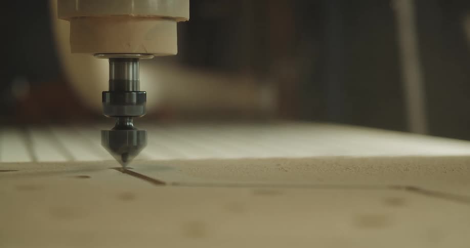 A machine carves into a piece of wood