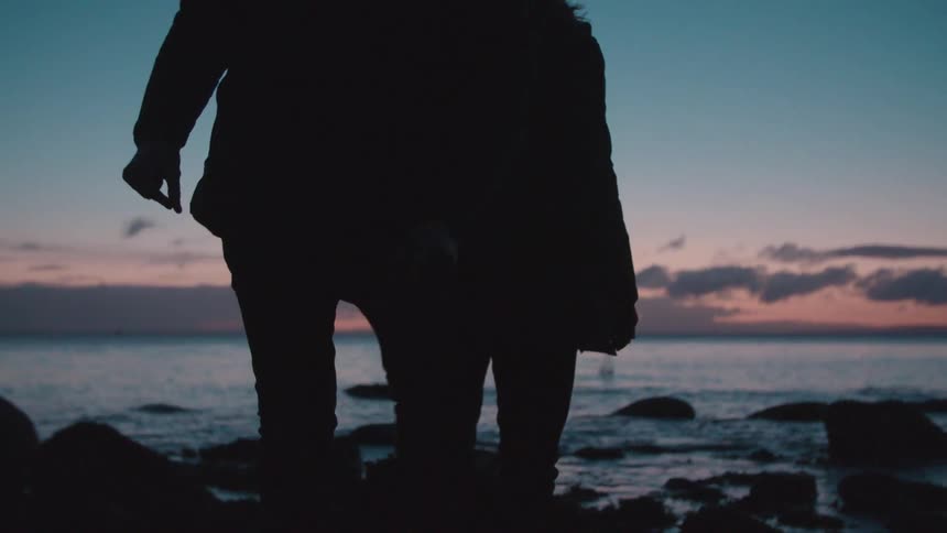 People walking on rocks at sunset