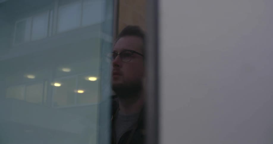 A man looks at his reflection in a window