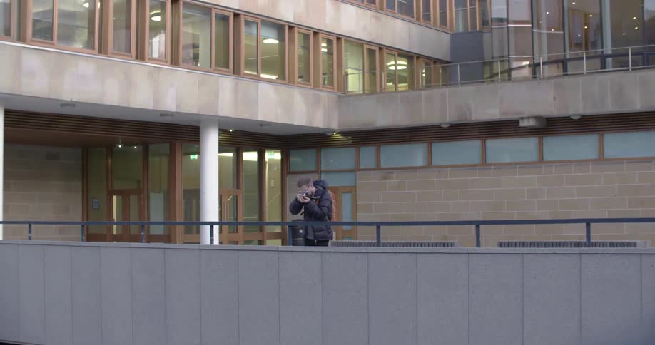Man photographs over the ledge of a building