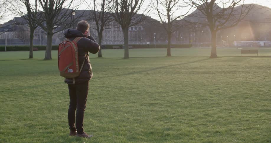 Man standing in open grassy area taking pictures