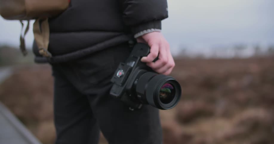 A person walks over to a field holding a camera