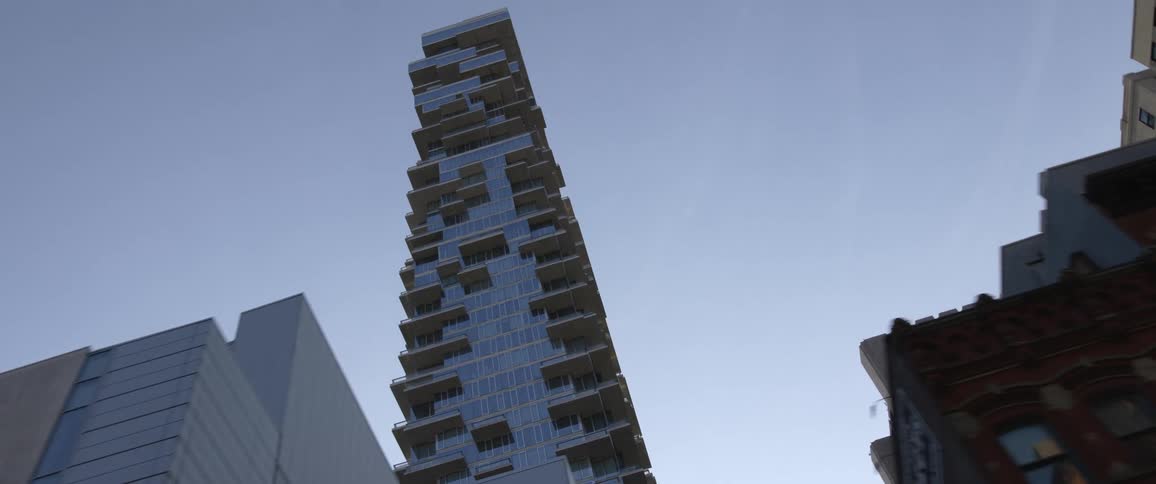 A stylish skyscrapers looms over smaller buildings in a metropolis during the day