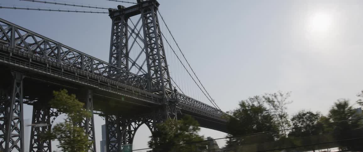 A large metal bridge has suspension cables holding up the driving platform