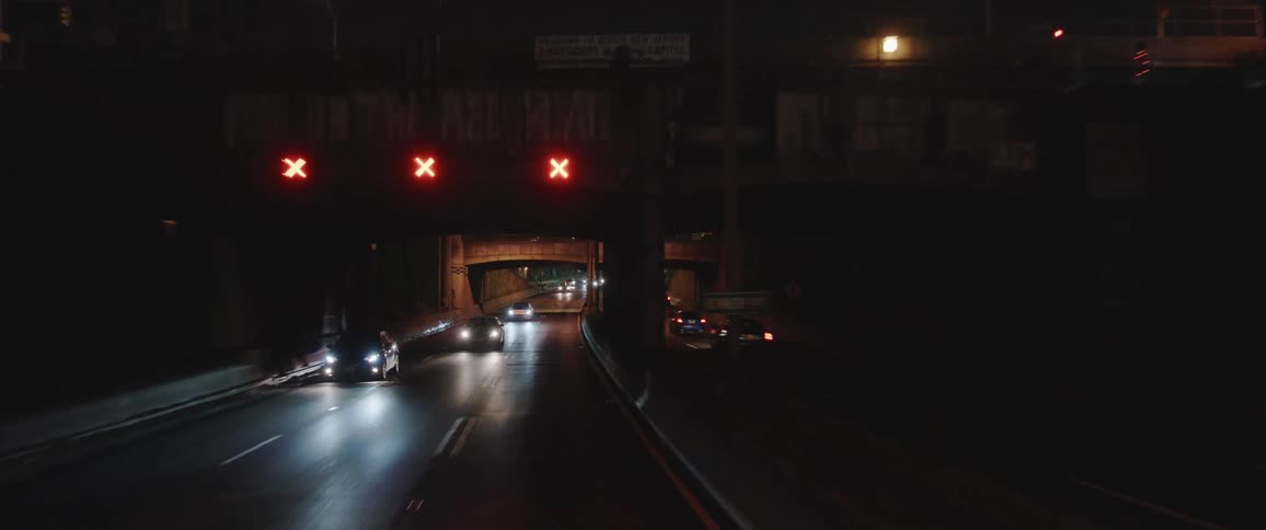 Vehicles driving down a highway through the city at night