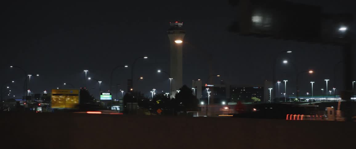 Traffic moves on a highway past a tower and city skyline at night