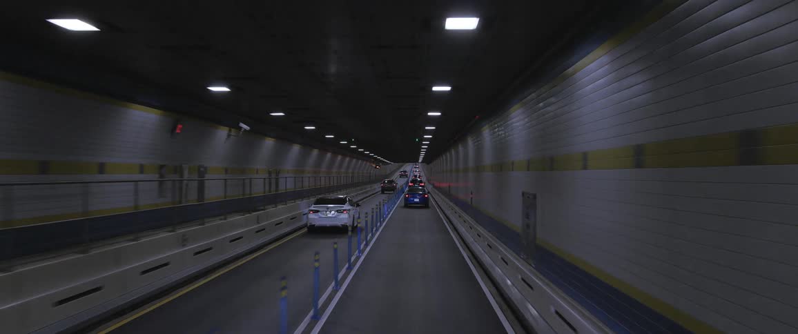 Traffic flows along tunnel decorated with yellow stripe on white tile
