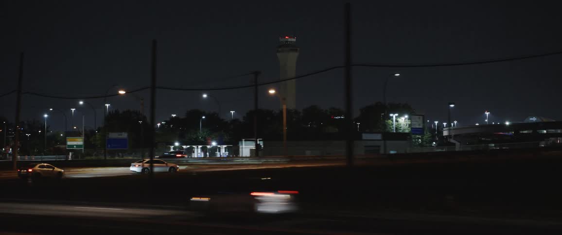 Moving on a road with other traffic and vehicles passing gas stations airport and under overpasses at night