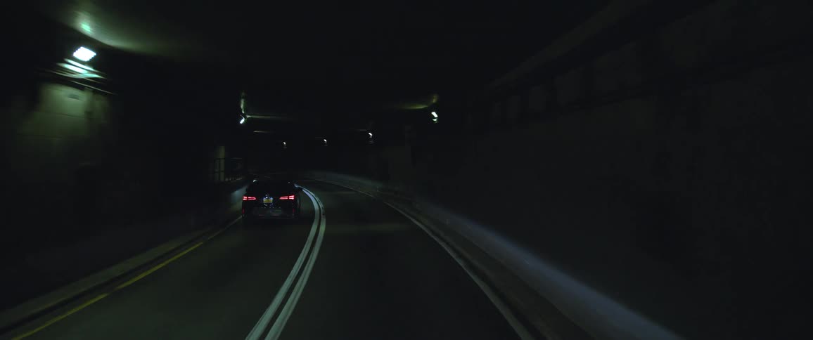 Car drives down the left lane of a tunnel filled with lights