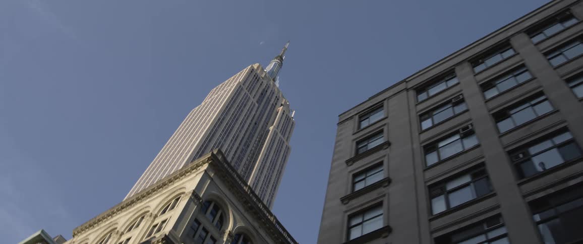 A skyscraper looms over smaller buildings in a metropolis on a clear day