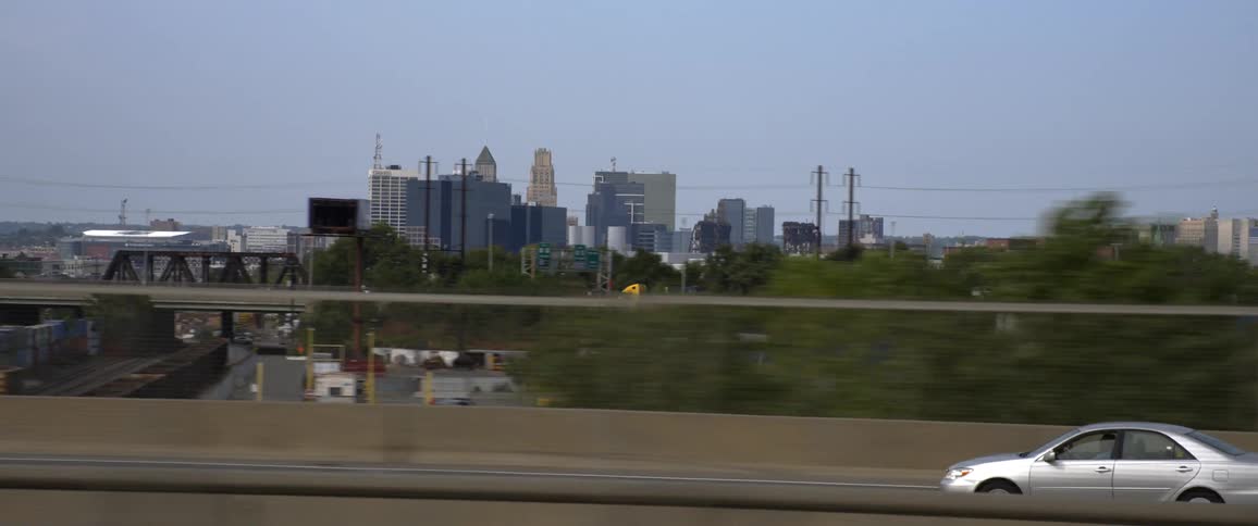 Moving down highway with silver car passing city and neighborhood