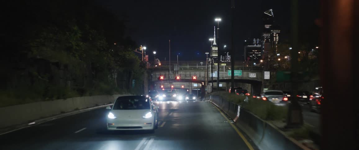Cars drive down a highway at night in the middle of the city