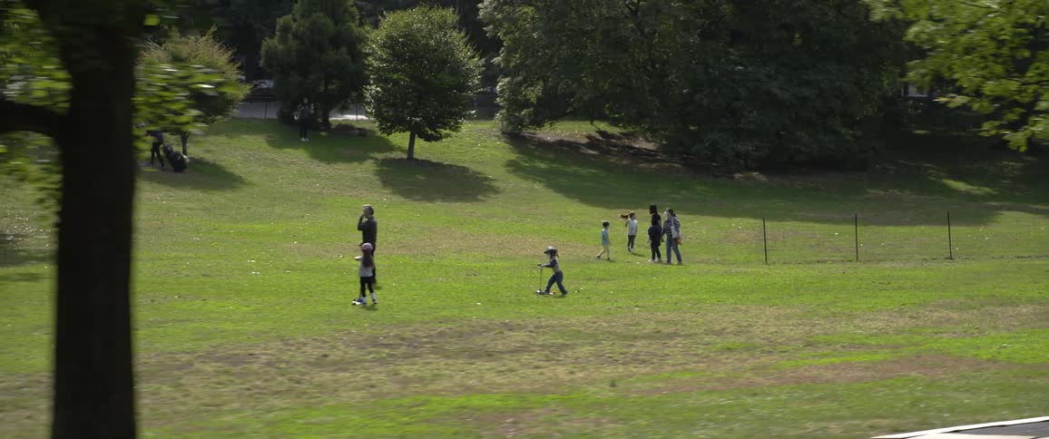 Family playing leisurely on the green grass near the tree line