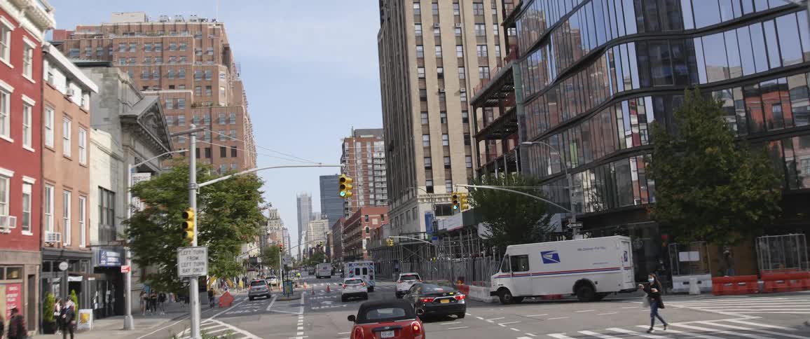 Cars traveling on a city street lined by buildings and skyscrapers