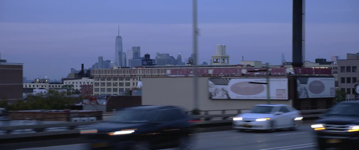 Traffic flows past graffiti covered buildings with fog covered skyline in background