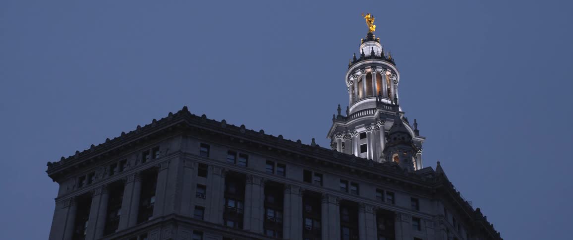 A large building with a dome and turrets is lit up in the evening