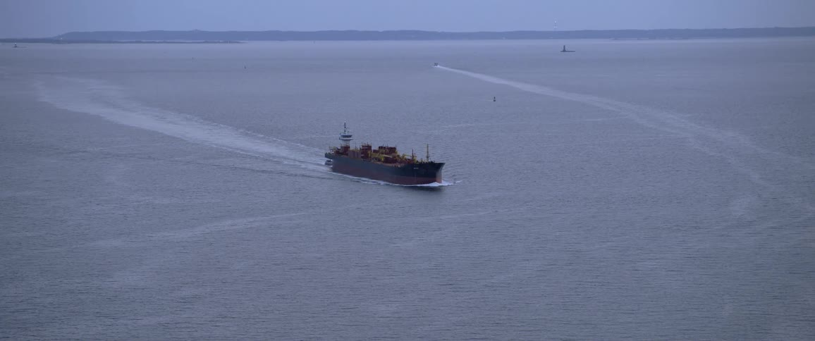 A barge loaded with containers moves across the water