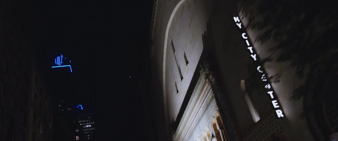 Lit sign and lights reveal buildings at night