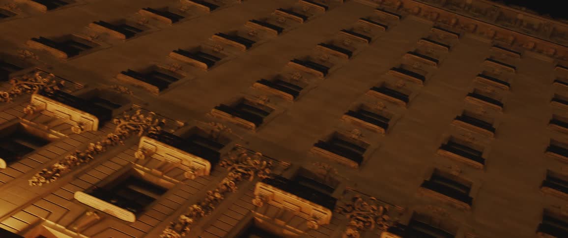 A tall building covered in windows towering overhead at night