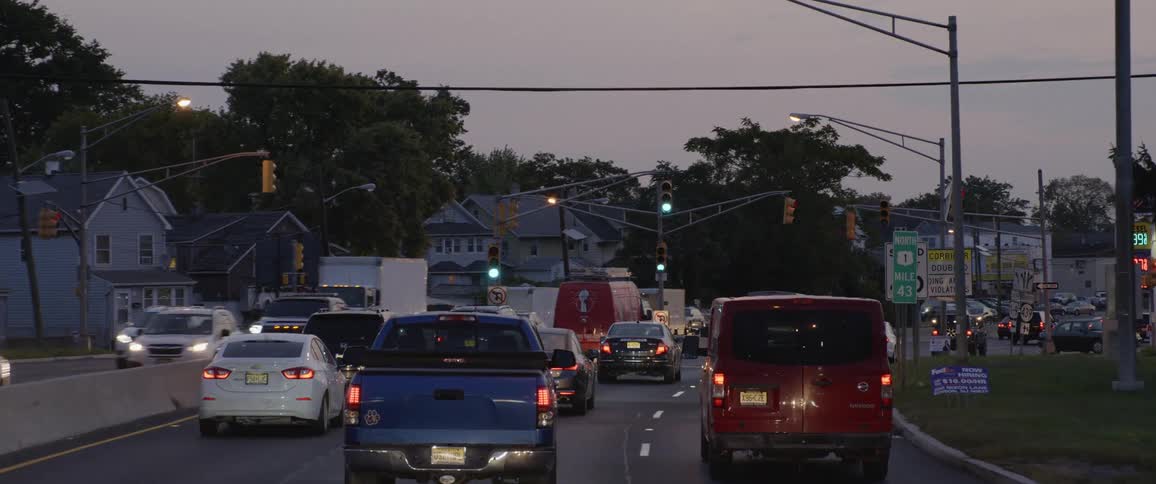 Cars are driving down a road at dusk