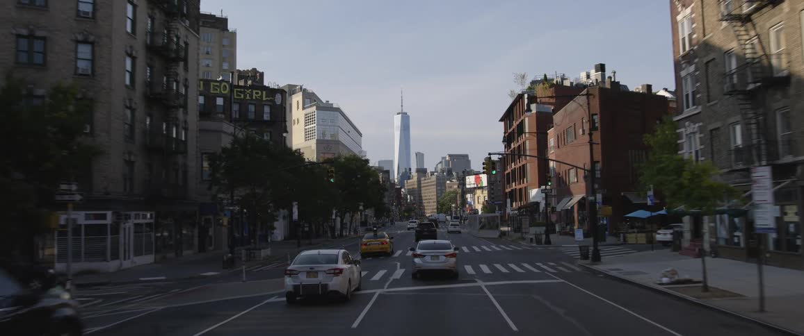 Traffic travels along a wide street in a metropolis on a sunny day