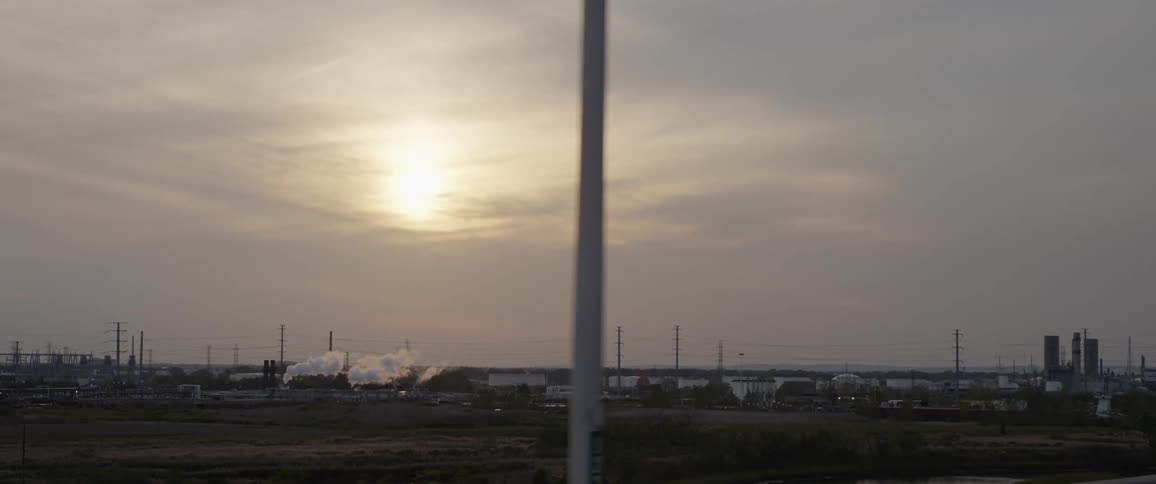 Smoke rising from a factory in the distance on an overcast day