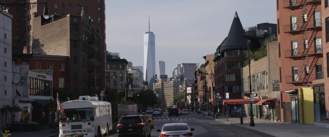 Vehicle drives down the highway with buildings and skyscraper in the background