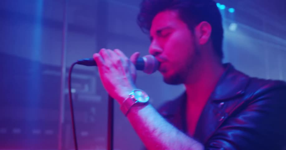 Singer and band perform on stage under lights
