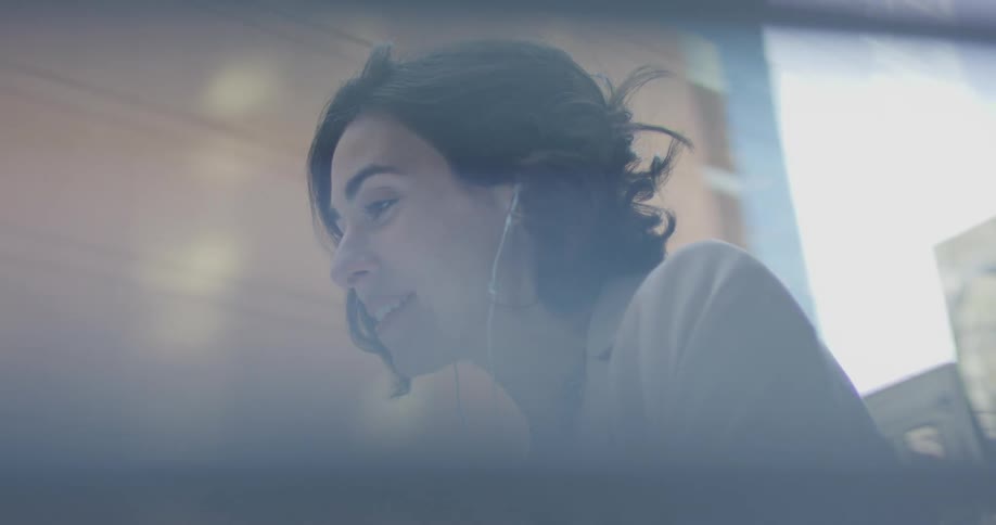 Woman outside of a window happily talking on the phone as she wears earbuds