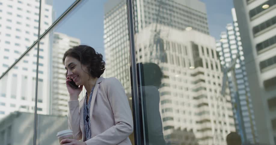 Young woman talking on her smartphone reclined against a building in the citys downtown