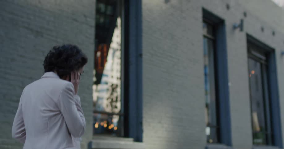 Young woman talks on the phone while walking near a building in the citys downtown
