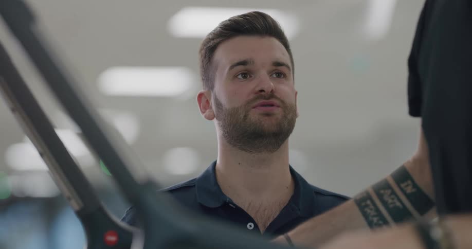 Personal trainer coaches man using exercise machine at gym