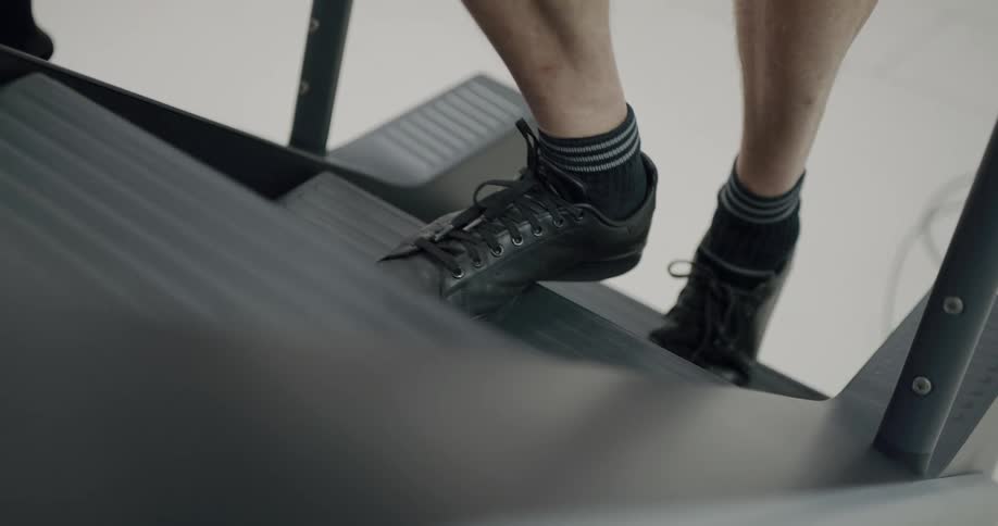 A man carefully walks up a stair climbing machine