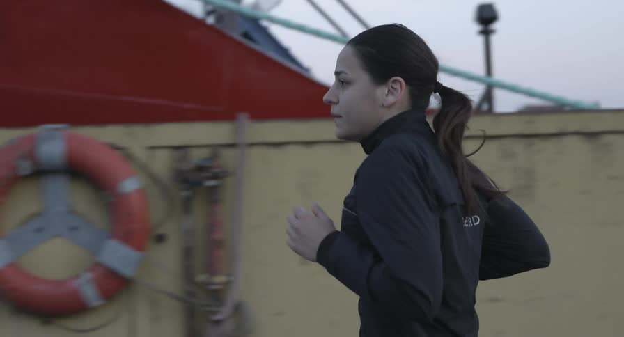 A woman jogs past a marina on a cold day