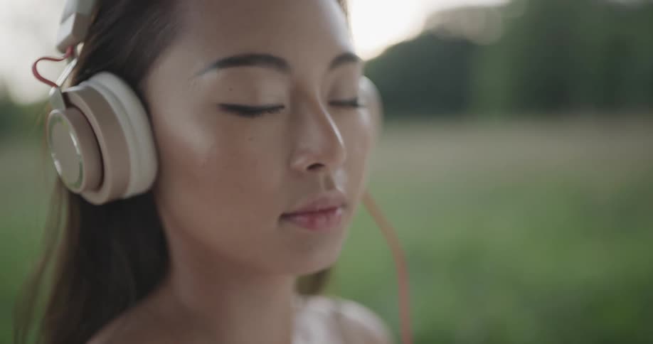 A female teenager stands outside listening to music with headphones