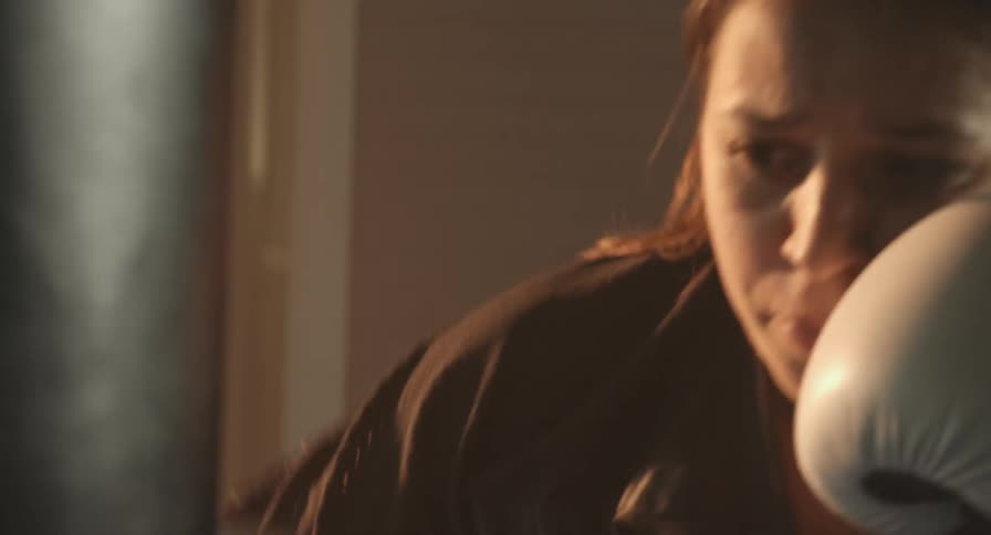 Woman wearing boxing gloves punches a hanging punching bag
